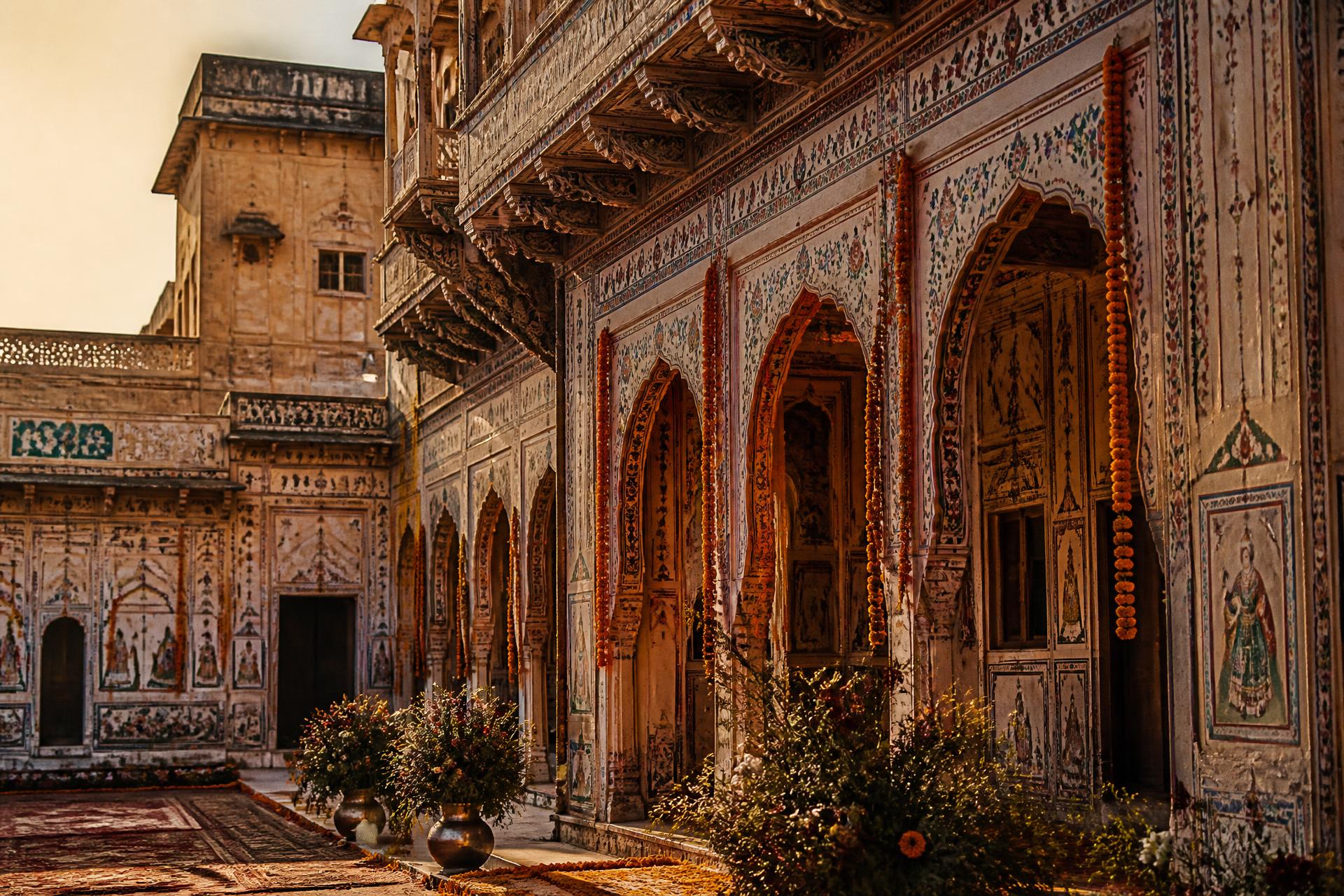 Frescoed haveli courtyard in Mandawa, Rajasthan, draped with marigold garlands at golden hour